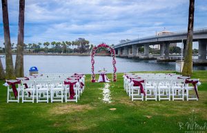 A wedding set up on the grass near water.