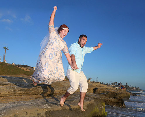wedding-fun-la-jolla-495 A man and woman jumping in the air on rocks.